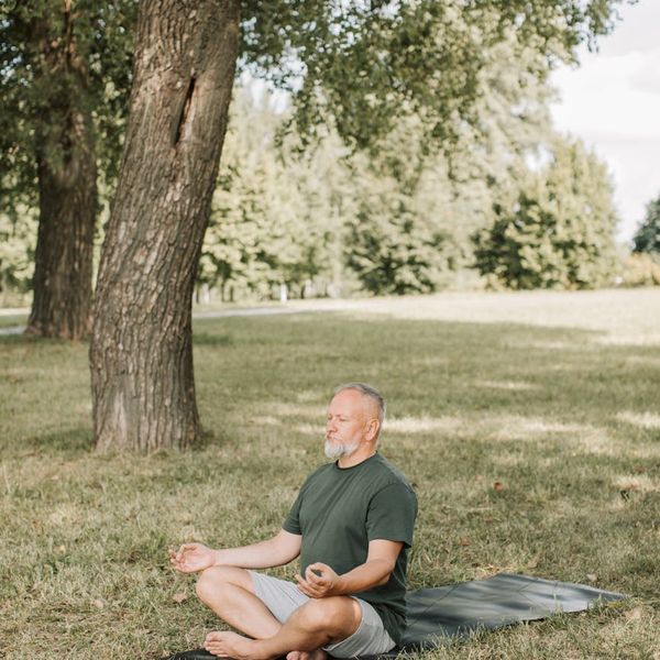 Person sitting cross-legged meditating in a serene natural environment with khaki accents.